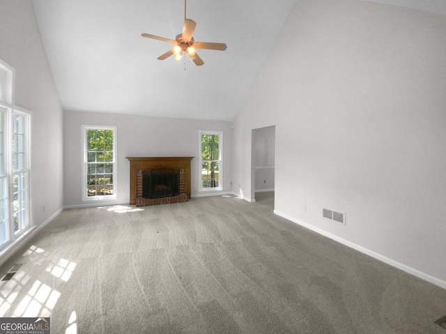 unfurnished living room with a wealth of natural light, light colored carpet, high vaulted ceiling, and a fireplace