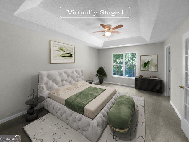 bedroom with carpet flooring, a tray ceiling, and ceiling fan