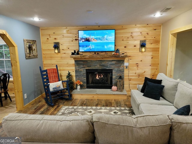 living room featuring wood-type flooring and a stone fireplace