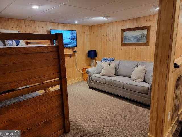 living room featuring carpet flooring, wooden walls, and a drop ceiling