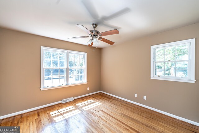 empty room featuring a wealth of natural light, ceiling fan, and light hardwood / wood-style floors