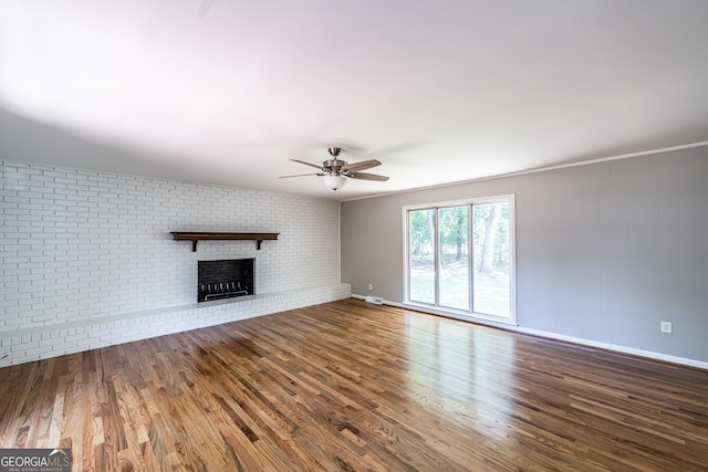 unfurnished living room with brick wall, ceiling fan, hardwood / wood-style flooring, and a fireplace