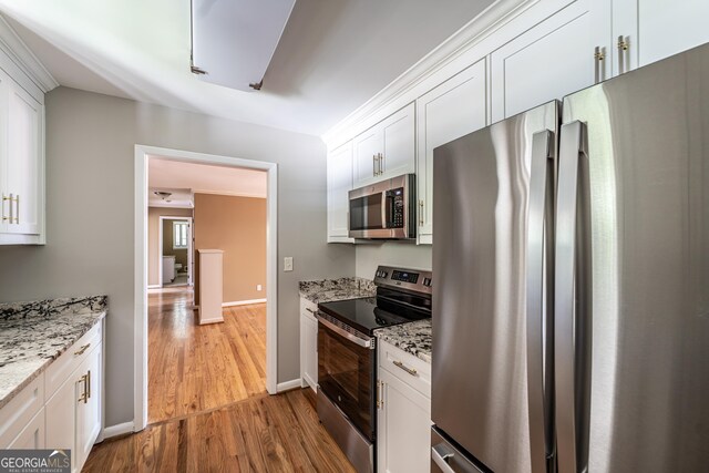 kitchen with light hardwood / wood-style flooring, light stone counters, appliances with stainless steel finishes, and white cabinetry