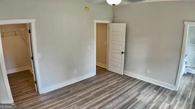 unfurnished bedroom featuring a walk in closet, a closet, and hardwood / wood-style flooring