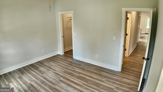 unfurnished bedroom featuring hardwood / wood-style floors, a walk in closet, and a closet