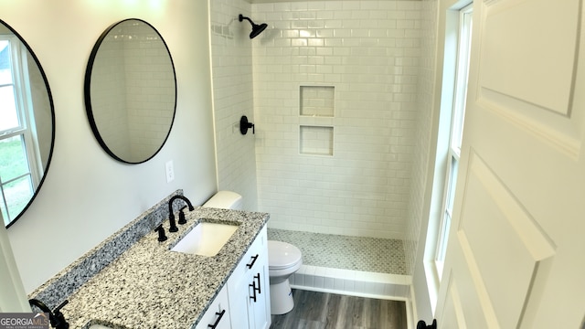 bathroom featuring vanity, toilet, hardwood / wood-style flooring, and a tile shower