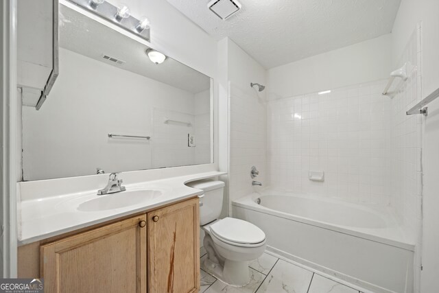 full bathroom featuring toilet, vanity, tiled shower / bath, and a textured ceiling