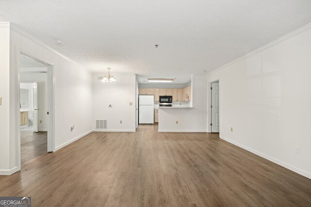 unfurnished living room featuring a notable chandelier, crown molding, hardwood / wood-style floors, and a textured ceiling