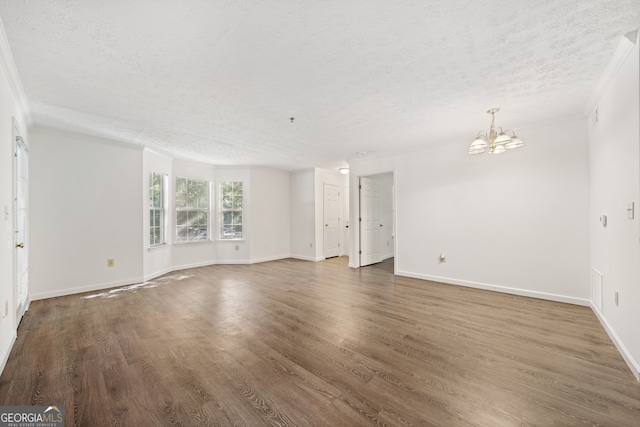 spare room with an inviting chandelier, a textured ceiling, and dark wood-type flooring