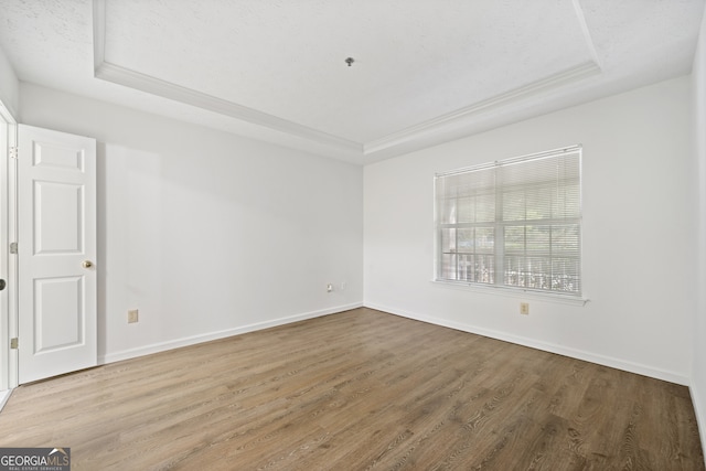 empty room featuring hardwood / wood-style flooring, a raised ceiling, and a textured ceiling