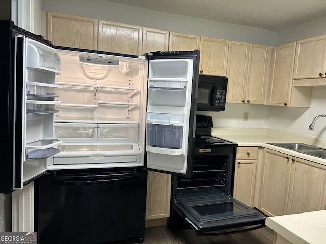 kitchen with light brown cabinetry, sink, dark hardwood / wood-style flooring, and black appliances