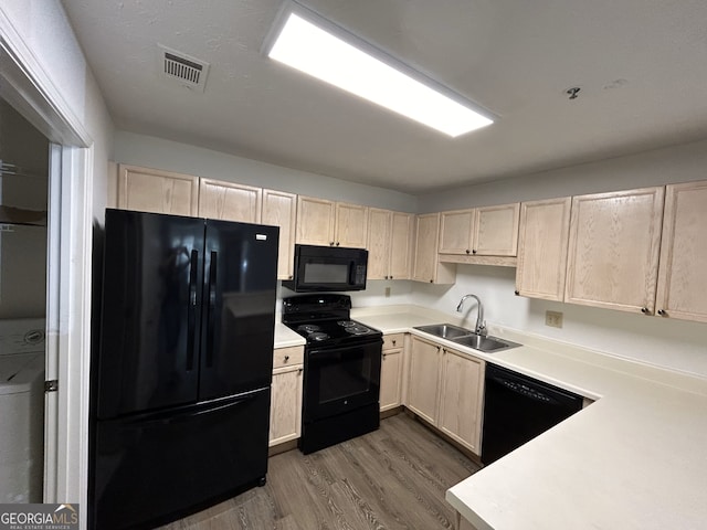 kitchen featuring washer / dryer, black appliances, wood-type flooring, light brown cabinets, and sink