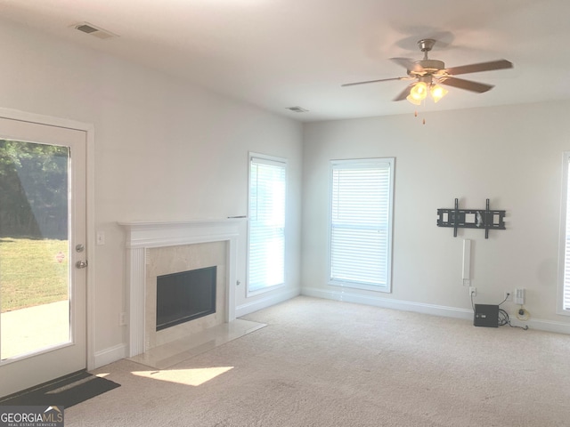 unfurnished living room featuring light colored carpet, ceiling fan, and a premium fireplace