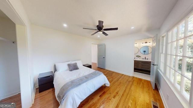 bedroom with sink, ensuite bathroom, ceiling fan, and light hardwood / wood-style floors