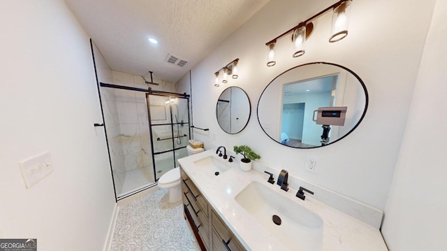 bathroom with a textured ceiling, a shower with shower door, toilet, and vanity