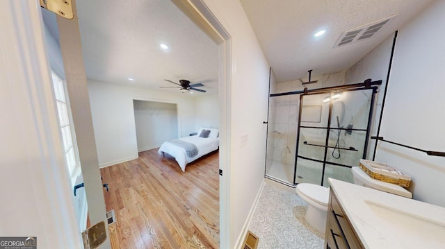 bathroom featuring an enclosed shower, hardwood / wood-style flooring, toilet, ceiling fan, and vanity