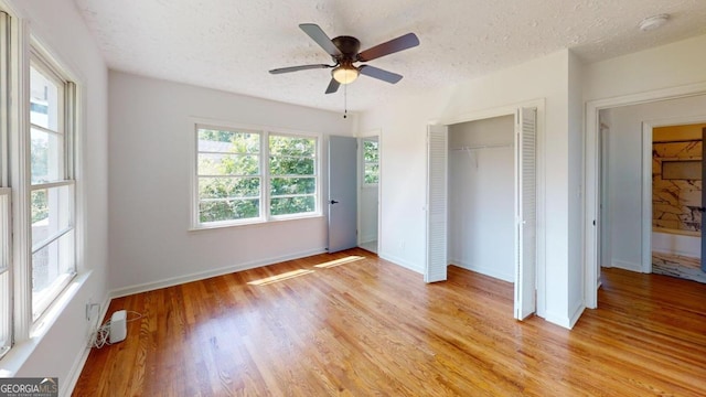 unfurnished bedroom featuring a textured ceiling, light hardwood / wood-style flooring, ceiling fan, and a closet