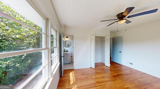 interior space with hardwood / wood-style floors, multiple windows, ceiling fan, and ensuite bath