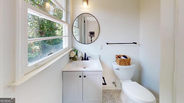 bathroom with vanity, toilet, a healthy amount of sunlight, and tile patterned floors