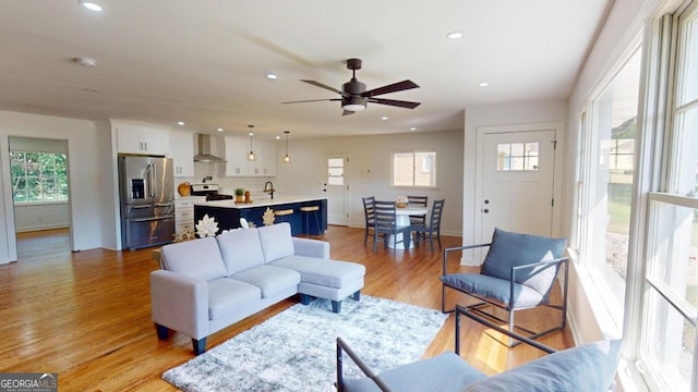 living room with light wood-type flooring, ceiling fan, and plenty of natural light