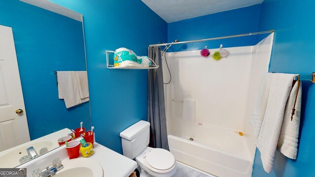 full bathroom with shower / bath combo with shower curtain, vanity, toilet, and a textured ceiling