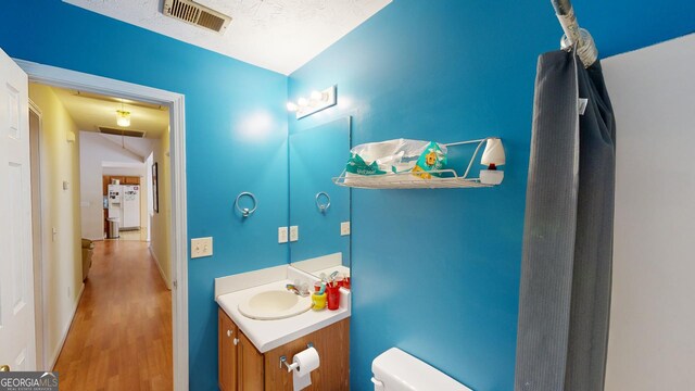 bathroom with hardwood / wood-style floors, toilet, and vanity