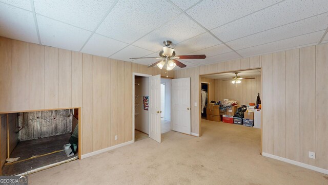 interior space with a paneled ceiling, ceiling fan, and carpet floors