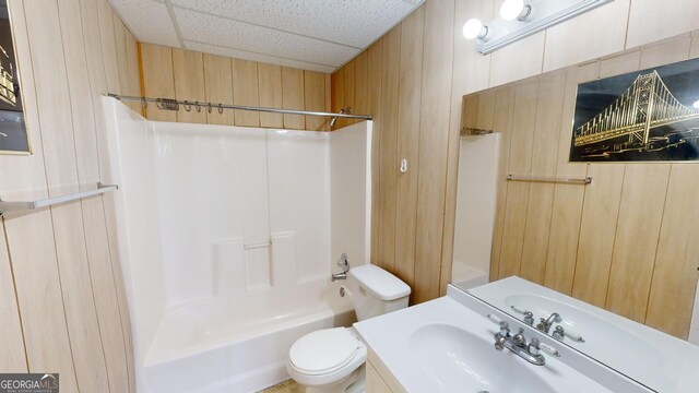 full bathroom featuring vanity, toilet, wood walls, and shower / bath combination