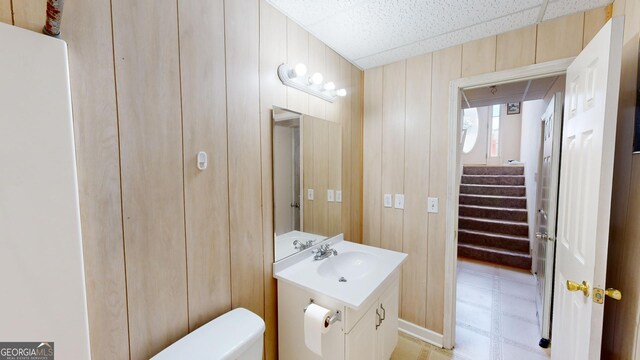 bathroom featuring vanity, toilet, and wood walls