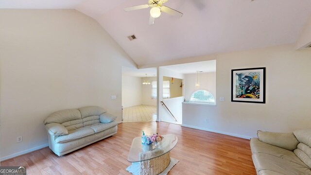 living room featuring lofted ceiling, ceiling fan with notable chandelier, and light wood-type flooring