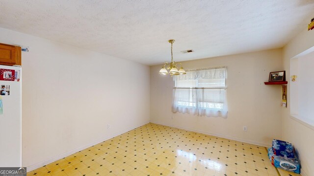 interior space with a textured ceiling, light tile patterned floors, and a notable chandelier