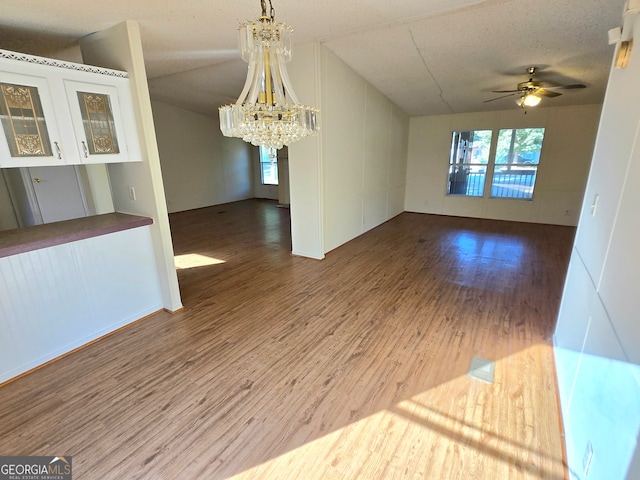 spare room with ceiling fan with notable chandelier, wood-type flooring, vaulted ceiling, and a textured ceiling