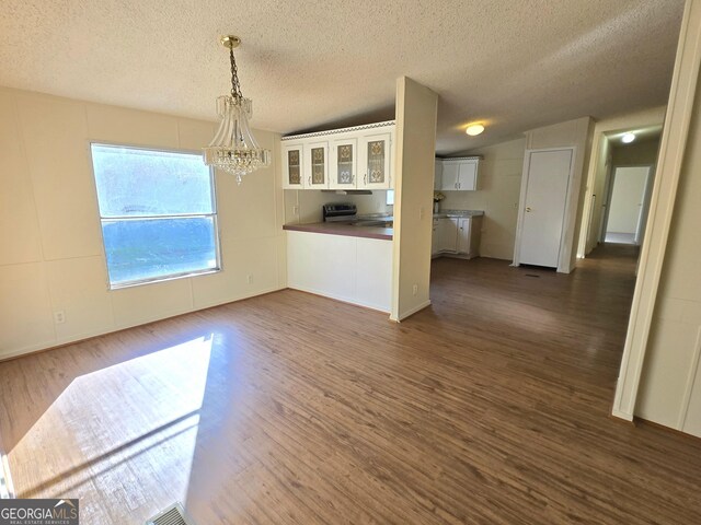 unfurnished dining area featuring a textured ceiling, dark hardwood / wood-style floors, and a notable chandelier