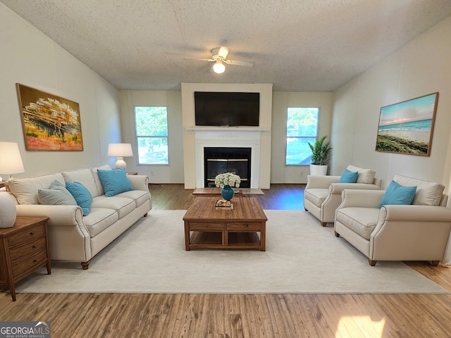 living room featuring a textured ceiling, light wood-type flooring, ceiling fan, and plenty of natural light