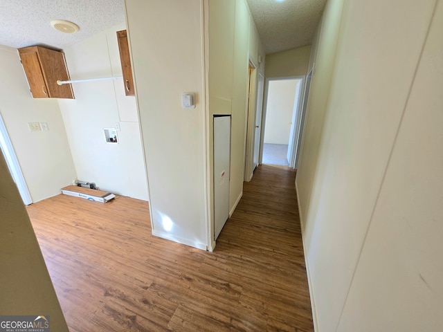 corridor with a textured ceiling and hardwood / wood-style flooring