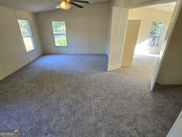 unfurnished room featuring carpet floors, a textured ceiling, vaulted ceiling, and ceiling fan