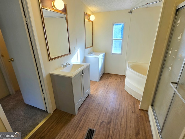 bathroom with independent shower and bath, a textured ceiling, vanity, and hardwood / wood-style flooring