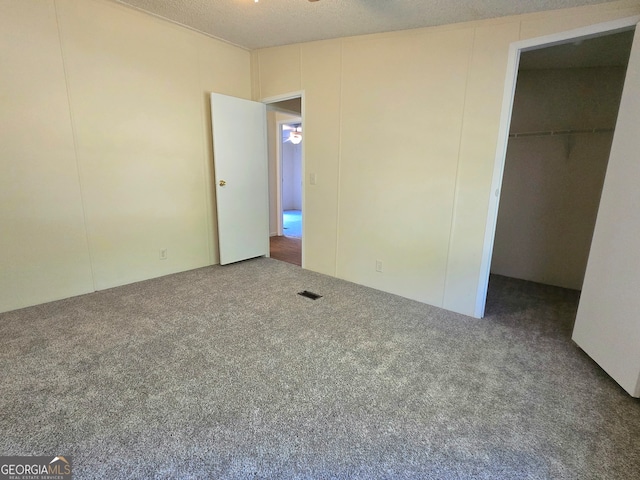 unfurnished bedroom with carpet floors, a textured ceiling, and a spacious closet