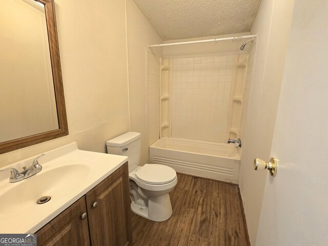 full bathroom with vanity, a textured ceiling, hardwood / wood-style flooring, shower / bathing tub combination, and toilet