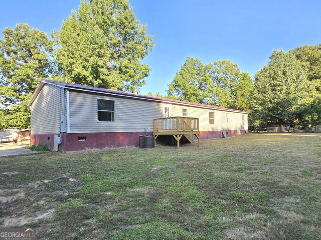 rear view of house with cooling unit, a yard, and a wooden deck