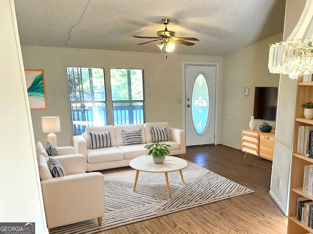 living room with wood-type flooring, a textured ceiling, and ceiling fan with notable chandelier