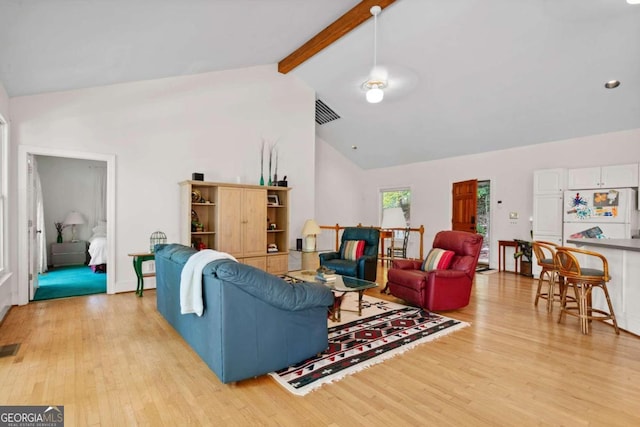 living room featuring high vaulted ceiling, light wood-type flooring, and beamed ceiling