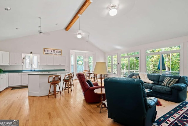 living room with beamed ceiling, light hardwood / wood-style floors, ceiling fan, and sink