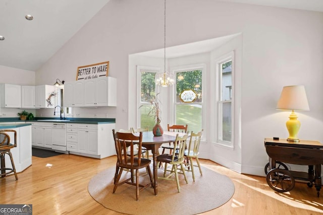 dining area with a chandelier, sink, light wood-type flooring, and high vaulted ceiling