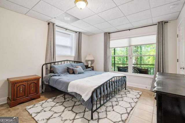 bedroom featuring multiple windows, light tile patterned floors, and a drop ceiling