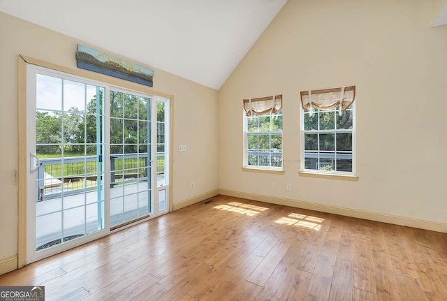 unfurnished room featuring high vaulted ceiling, visible vents, baseboards, and wood finished floors