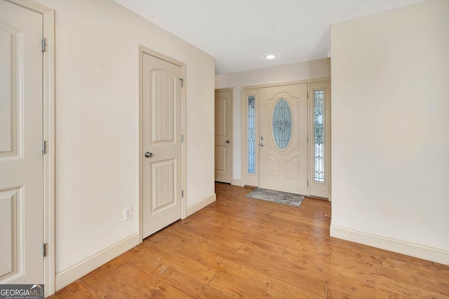 entryway with baseboards, a textured ceiling, and light wood-style floors