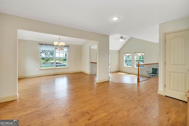 interior space featuring baseboards, vaulted ceiling, light wood finished floors, and ceiling fan with notable chandelier