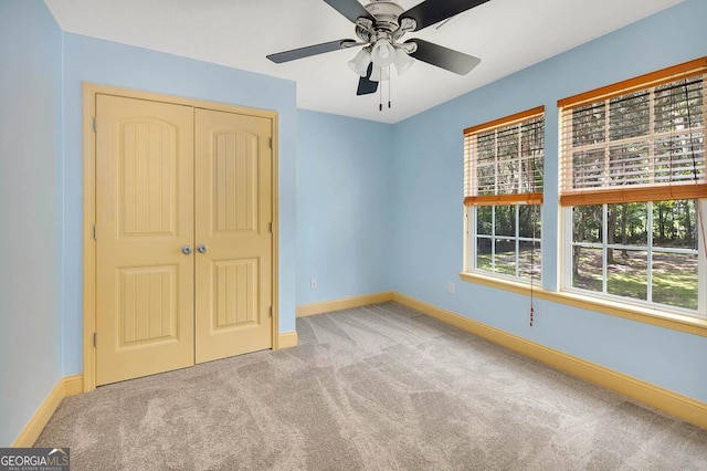 unfurnished bedroom featuring a ceiling fan, a closet, carpet flooring, and baseboards