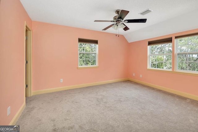 carpeted spare room with a ceiling fan, visible vents, vaulted ceiling, and baseboards